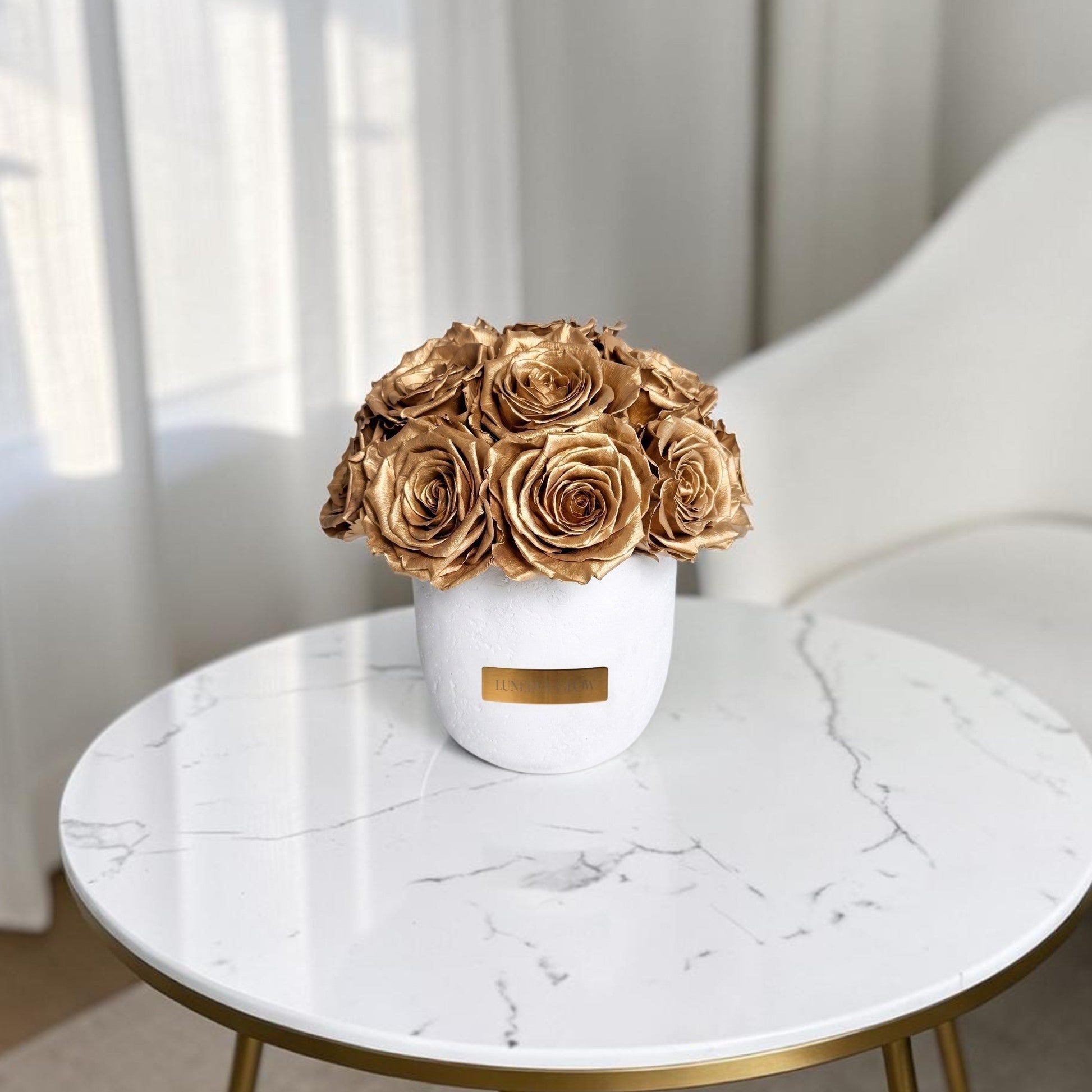 Weisse Betonvase mit goldenen konservierten Rosen. Lifestyle